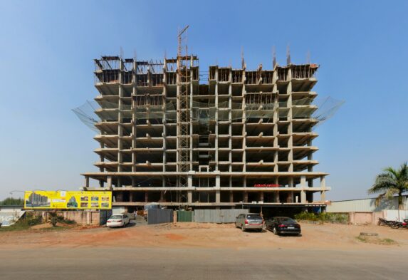 a large building under construction with cars parked in front of it