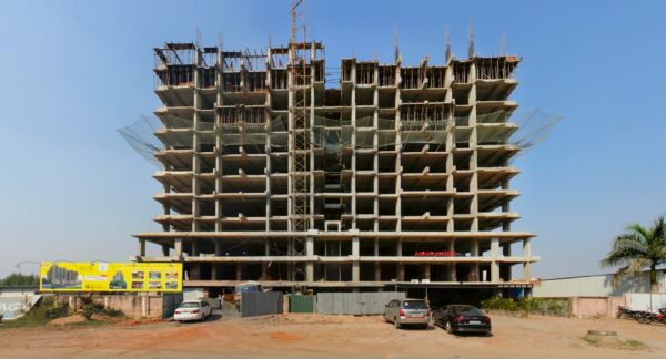 a large building under construction with cars parked in front of it