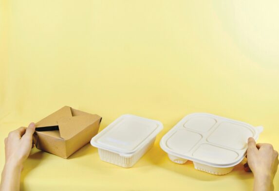 a person holding a box and two take out containers
